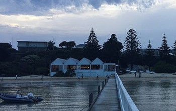 a jetty looking over calm water to houses